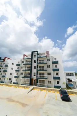 a large white building with a car parked in a parking lot at SoliMar Caribeño in Boca Chica