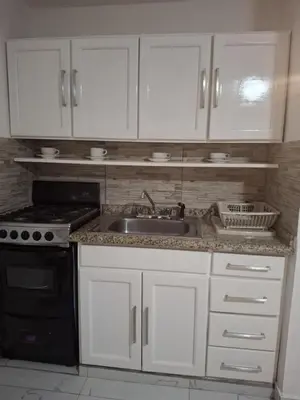 a kitchen with white cabinets and a sink and a stove at Beautiful condo in Sosua walking distance from everything in Sosúa
