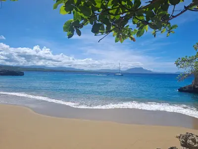 a beach with a sail boat in the water at Beautiful condo in Sosua walking distance from everything in Sosúa