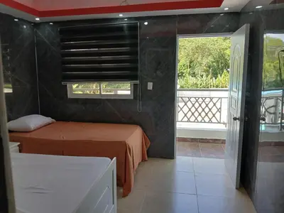 a bedroom with two beds and a window and a balcony at Paraíso Vacacional FERNANDO in Polo