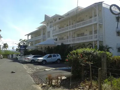 a large white building with cars parked in a parking lot at Los Balcones in Sosúa