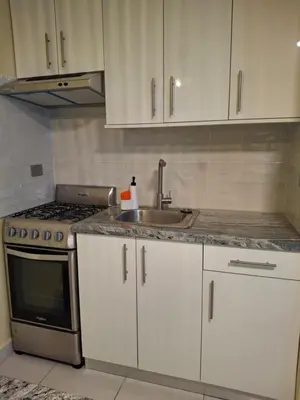 a kitchen with white cabinets and a sink and a stove at Modern condo in middle of Sosua in Sosúa