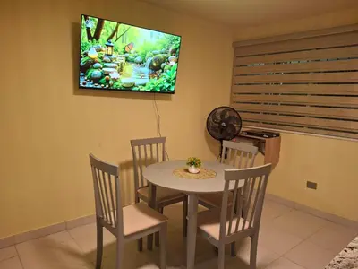 a dining room with a table and chairs and a tv at Modern condo in middle of Sosua in Sosúa
