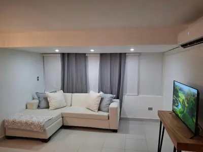 a living room with a couch and a flat screen tv at Modern condo in middle of Sosua in Sosúa