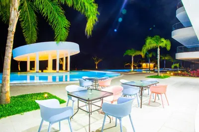 a patio with tables and chairs in front of a pool at Cana Rock Star D208 Jaccuzi Pool Golf and Private Beach in Punta Cana