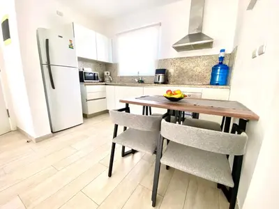 a kitchen with a wooden table with chairs and a refrigerator at Los corales 1Bedroom Apartament Close to the Beach Central los corales RD in Punta Cana