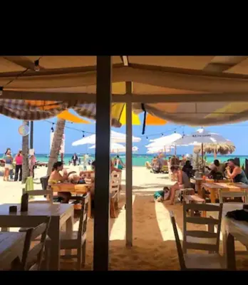 people sitting at tables on the beach under umbrellas at Los corales 1Bedroom Apartament Close to the Beach Central los corales RD in Punta Cana