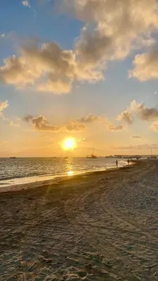 a beach with the sun setting in the ocean at Los corales 1Bedroom Apartament Close to the Beach Central los corales RD in Punta Cana