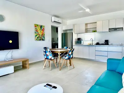 a living room with a table and chairs and a kitchen at Rheia Properties - SANTA FE in Sosúa