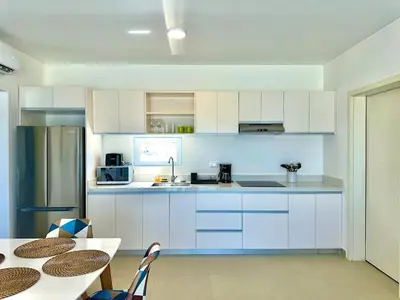 a kitchen with white cabinets and a table with chairs at Rheia Properties - SANTA FE in Sosúa