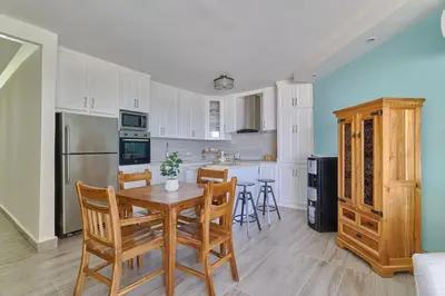 a kitchen with white cabinets and a wooden table and chairs at Costa Del Sol Juan Dolio 2BR Sunset, Beach Front in Juan Dolio