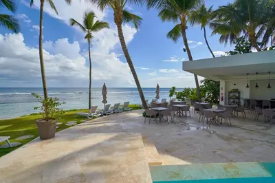 a restaurant on the beach with palm trees and the ocean at Caribbean Paradise Aquarella 22th in La Puntica de Juan Dolio