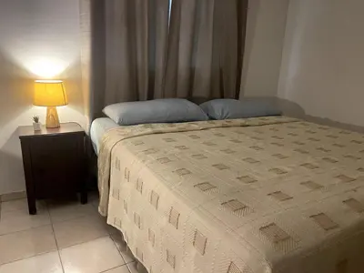 a bedroom with a bed and a lamp on a table at Acogedor apartamento en Bella Vista, Casa Caribe in Santo Domingo