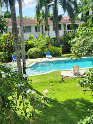 a swimming pool with two lawn chairs and palm trees at KERY-OASIS 2bdr with pool close to the Beach in Las Terrenas