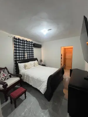 a bedroom with a large bed and a chair at Villa con Piscina en la Romana in La Romana