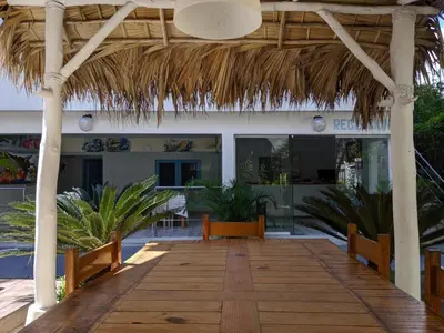 a wooden walkway in front of a building with a thatched roof at Casa Brisa Mar Hotel in Las Terrenas