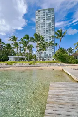 a boardwalk leading to a beach with a tall building at Luxurious Caribbean Aquarella 10th in La Puntica de Juan Dolio