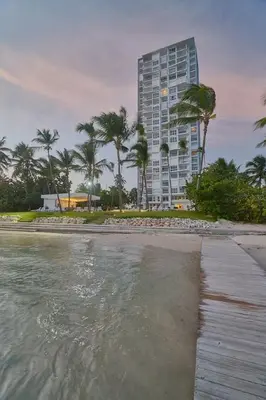a beach with a tall building and palm trees at Aquarella Caribbean Blue Summer Special GateAway in La Puntica de Juan Dolio