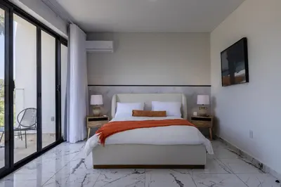 a bedroom with a bed and a tv on a wall at Perla 8- Exclusiva Moderna Villa 4 Habitaciones y Piscina in Sosúa