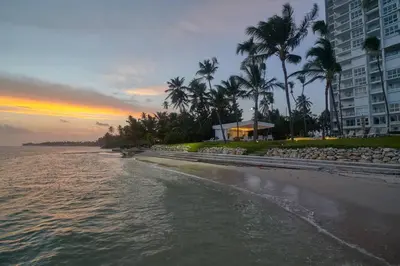 a beach with palm trees and a building and the ocean at Aquarella Deluxe Caribbean Paradise in La Puntica de Juan Dolio