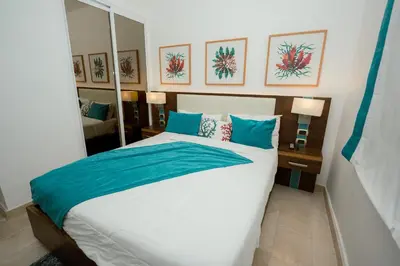 a bedroom with a large bed with blue pillows at Apartamento moderno en Cana Rock - Punta Cana in Punta Cana