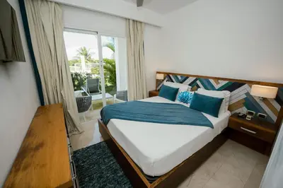 a bedroom with a bed with blue pillows and a window at Apartamento moderno en Cana Rock - Punta Cana in Punta Cana