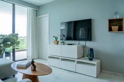 a white living room with a tv on a wall at Apartamento moderno en Cana Rock - Punta Cana in Punta Cana