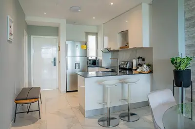 a kitchen with a counter and stools in it at Apartamento moderno en Cana Rock - Punta Cana in Punta Cana