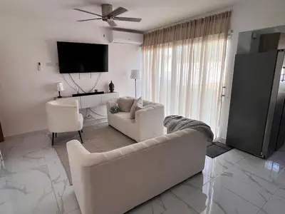 a white living room with a couch and a tv at The Ocean Romana in La Romana