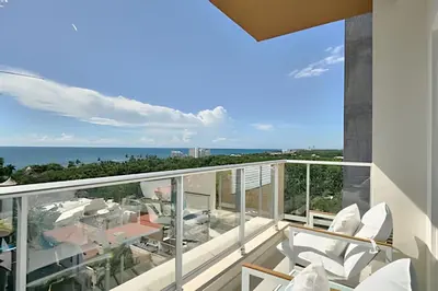 a balcony with white chairs and a view of the ocean at Costal View Apt. Walkable To Beach & Restaurants in Juan Dolio