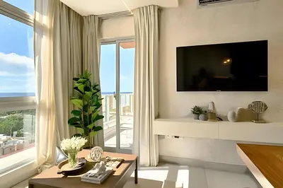 a living room with a tv and a large window at Costal View Apt. Walkable To Beach & Restaurants in Juan Dolio