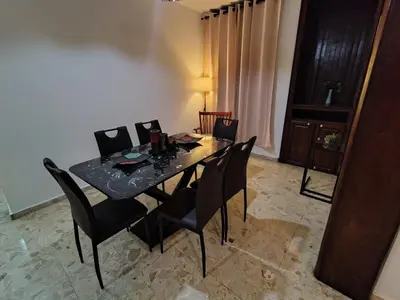 a dining room table with black chairs and a table and a lamp at Céntrico y acogedor apartartamento con Wifi y Parqueo gratis in Santo Domingo