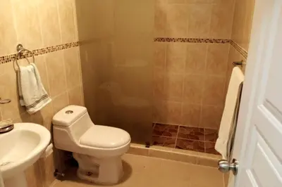 a bathroom with a toilet and a sink and a shower at Exclusive Apartment Free WiFi and Parking in Santo Domingo