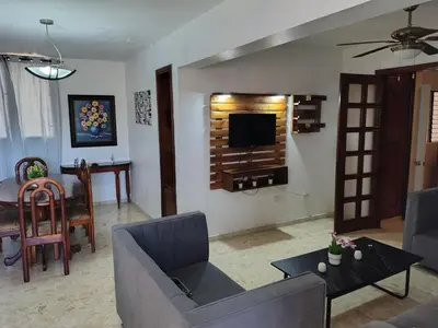 a living room with a couch and a tv on a wall at Exclusive Apartment Free WiFi and Parking in Santo Domingo