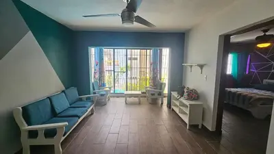 a living room with a blue couch and a bed at Apartment 150m from the beach with pool in Boca Chica