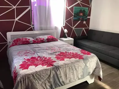 a bedroom with a bed with red flowers on it at Apartment 150m from the beach with pool in Boca Chica