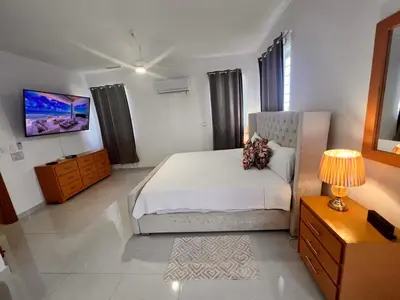 a bedroom with a large white bed and a television at Popsy Villa 3 Bedrooms with Pool in Puerto Plata