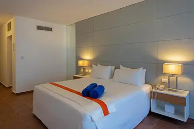 a large white bed with two blue pillows on it at Viva Heavens by Wyndham, A Trademark All Inclusive in San Felipe de Puerto Plata