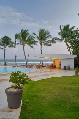 a resort with a pool and palm trees and the ocean at Beachfront FL21 Con Tina Aquarella in La Puntica de Juan Dolio