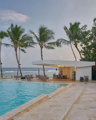 a swimming pool next to a beach with palm trees at Beachfront FL21 Con Tina Aquarella in La Puntica de Juan Dolio