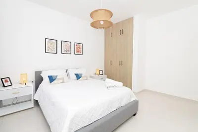 a white bedroom with a white bed and a wooden cabinet at Cozy 1-BR Apartment in Sunshine Bayahibe in San Rafael del Yuma