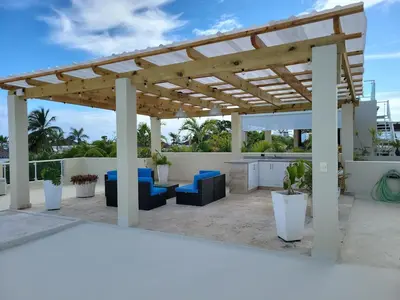 a patio with a wooden pergola and blue chairs at Villa Serenity In The Sun in Sosúa