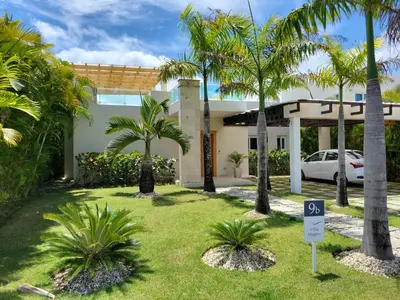 a house with palm trees in front of it at Villa Serenity In The Sun in Sosúa
