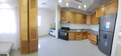 a kitchen with wooden cabinets and a stainless steel refrigerator at Apartamento in Santo Domingo