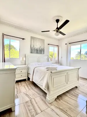 a white bedroom with a bed and a ceiling fan at Beautiful and confortable apt in Puerto Plata
