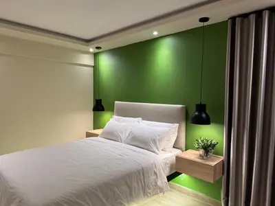 a bedroom with a white bed with a green wall at Caonabo35 Elegancia Boutique en Santo Domingo 2 in Santo Domingo