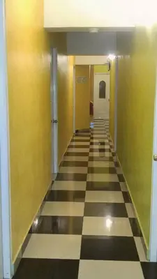 a hallway with yellow walls and a checkered floor at Hotel Gazcue in Santo Domingo