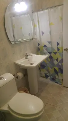 a bathroom with a toilet and a sink and a mirror at Hotel Gazcue in Santo Domingo