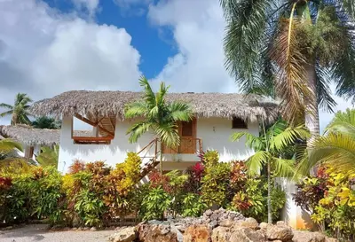 a white house with palm trees and plants at Apartamento La Palmeras - 3 Pax, 5 Min de La Playa in Las Galeras