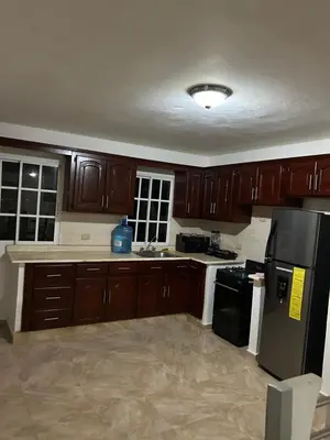 a kitchen with wooden cabinets and a black refrigerator at Villas Burnette in Camú
